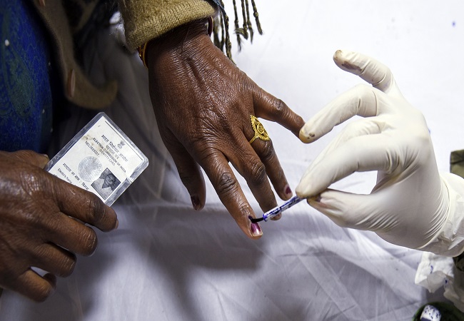 An electoral staff marks ink to a voter after the casting of her vote