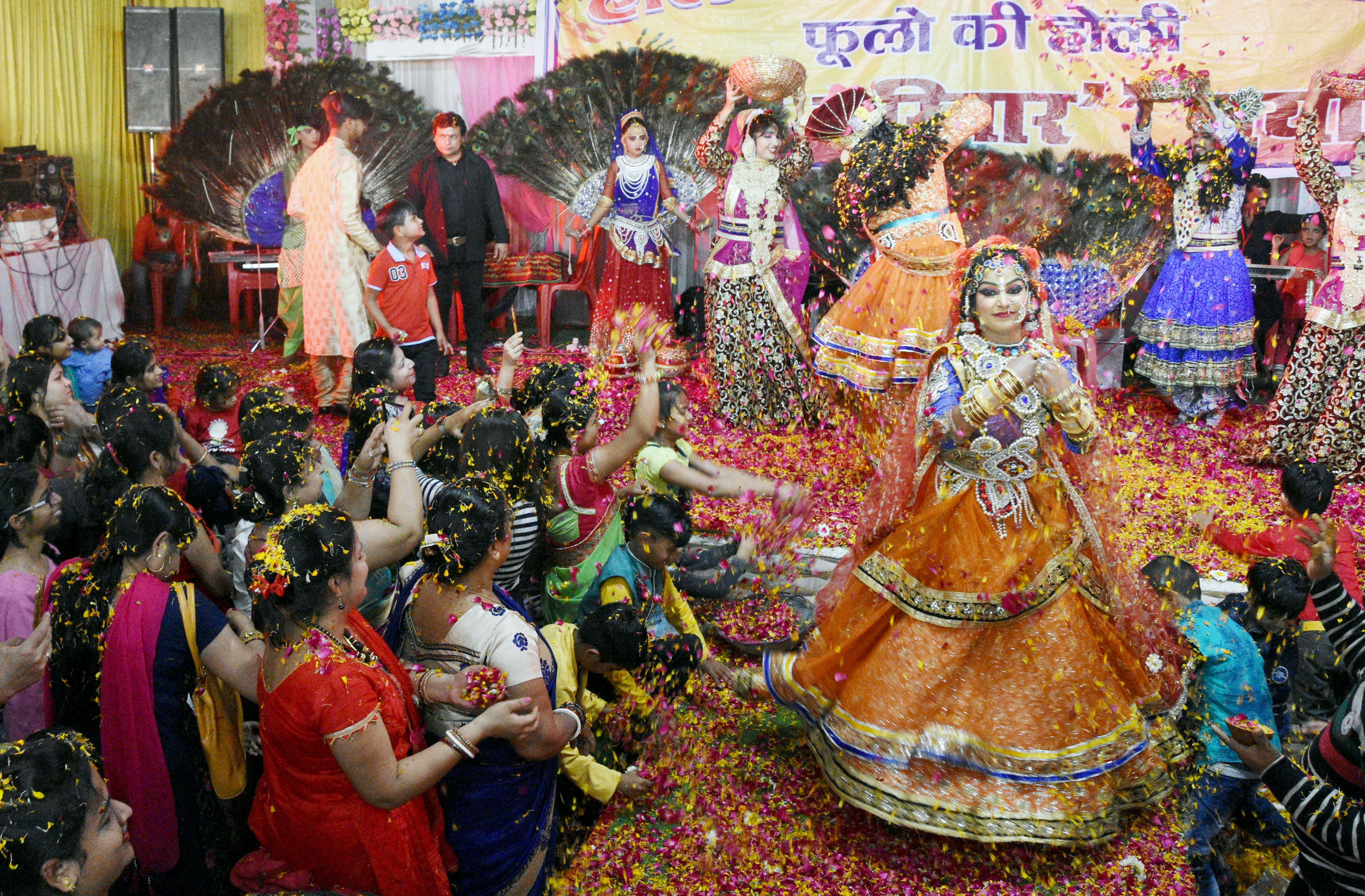 Artists dressed up lord krishna and radha play with flower petals during the holi celebration