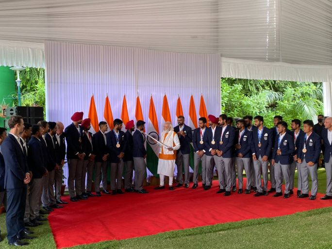 Men's hockey team presents PM Modi with autographed hockey.