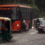 Vehicles make their way through a waterlogged road during heavy rainfall