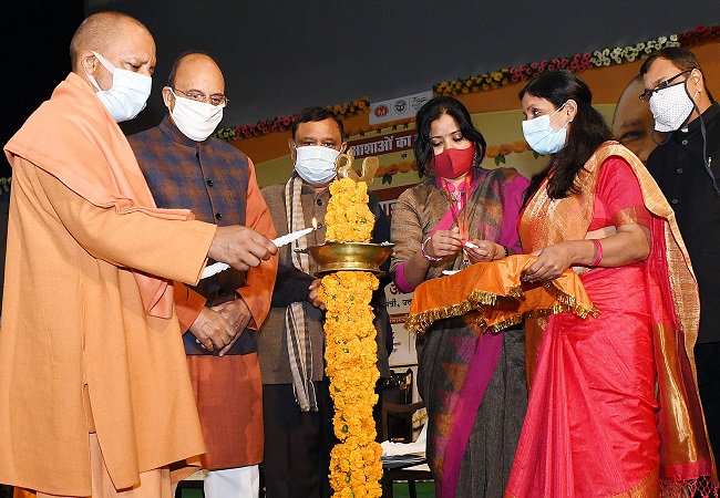 Yogi Adityanath lights a lamp during the event Ashaon Ka Sammelan