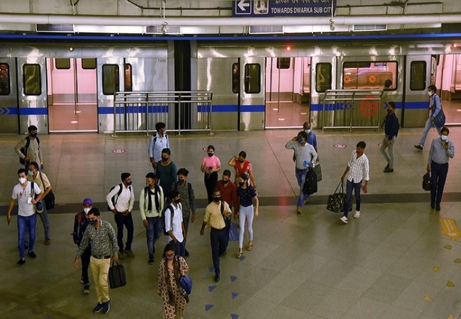 Commuters come out from a metro couch as Delhi metro service resumes during the unlocking