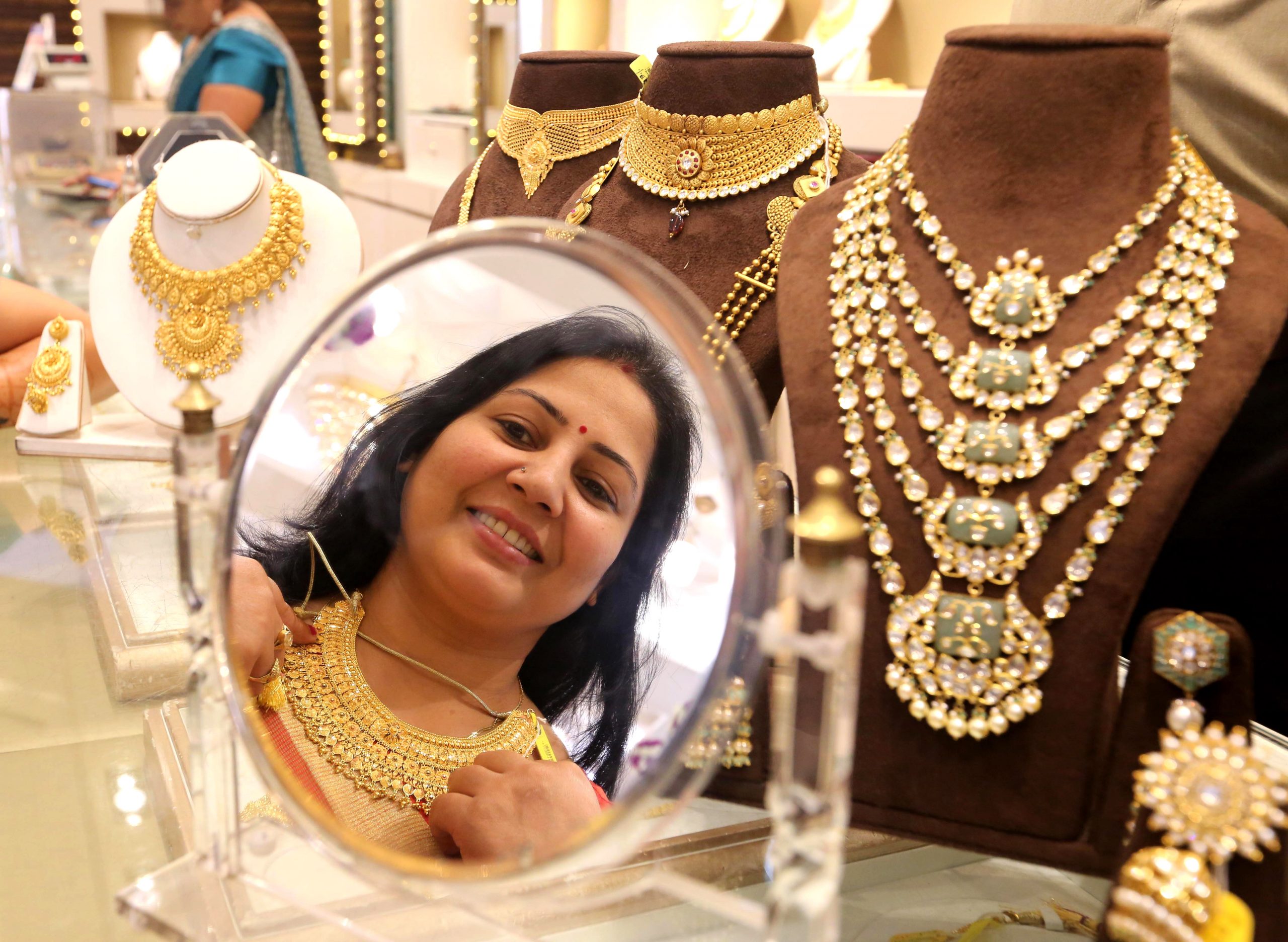 A Woman trying gold ornaments to purchase at a jewellery shop